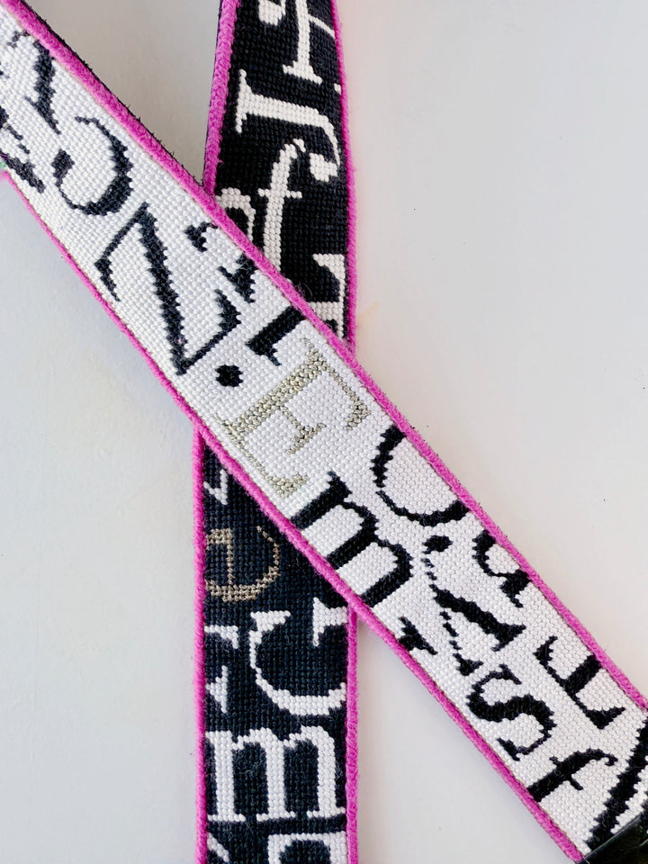Close-up of a patterned belt with text on a light gray background